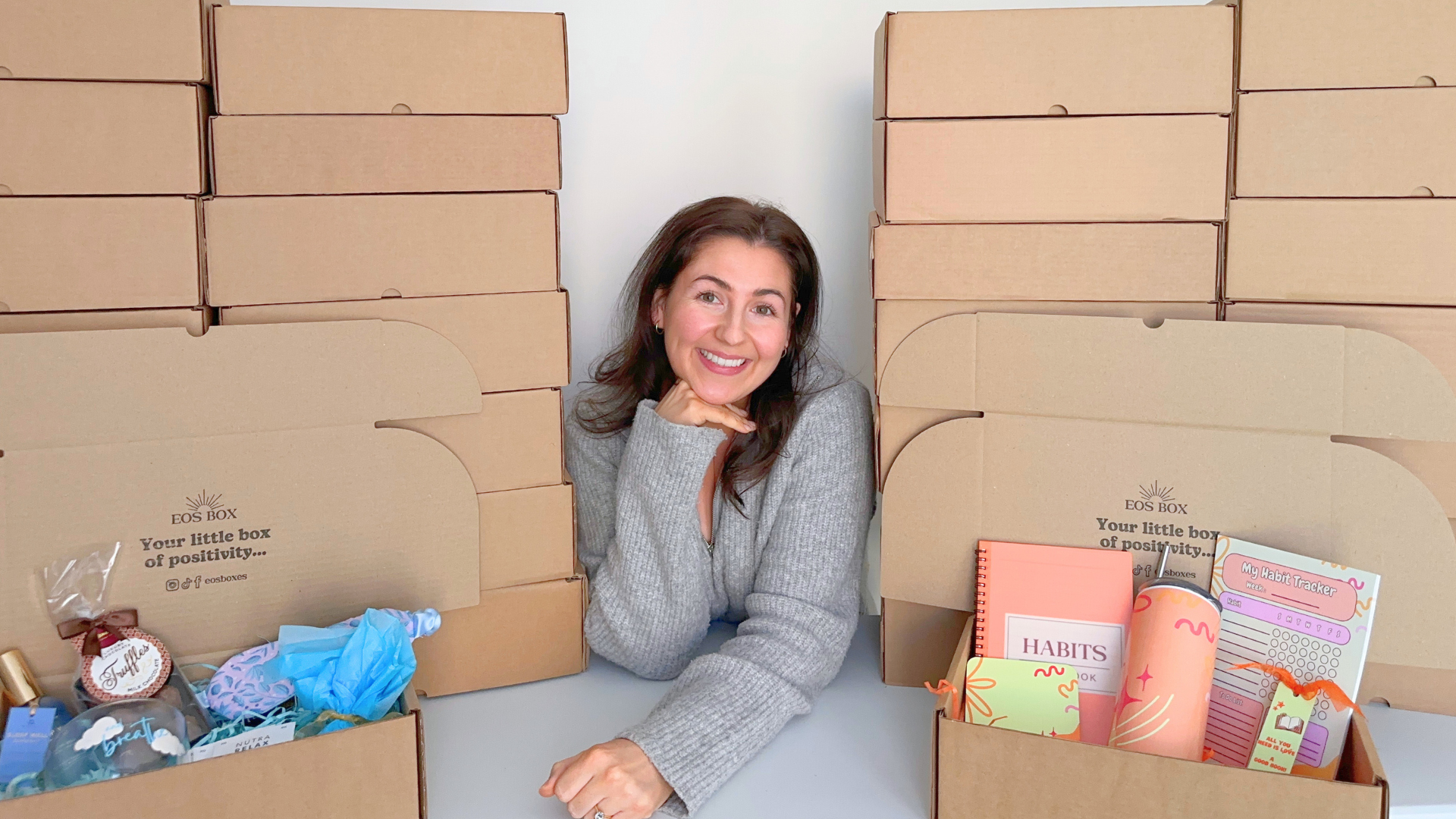 EOS BOX founder Georgina McGarry standing between two of her self care and personal development gift boxes.