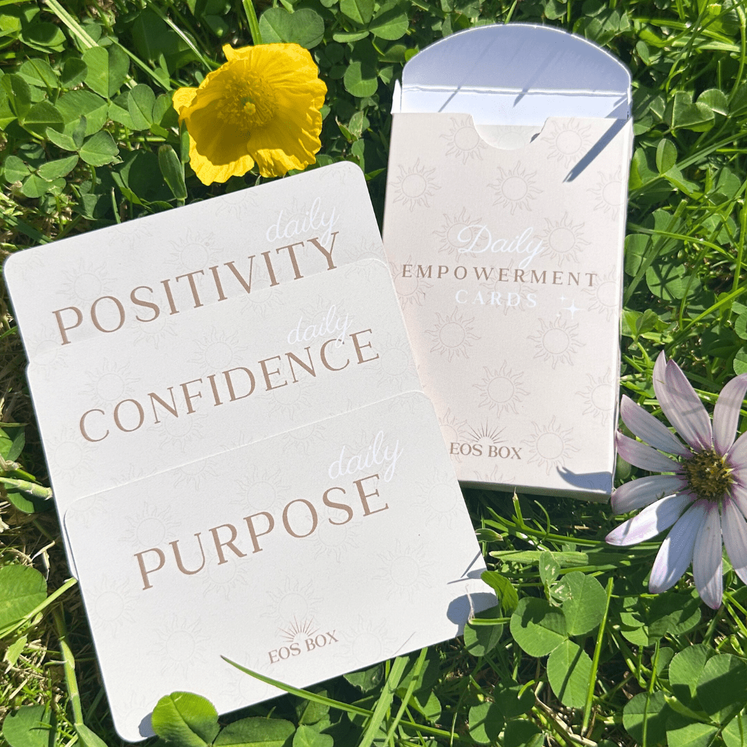 Pack of positivity affirmation cards outside on a field with clovers, buttercups and flowers in the background.